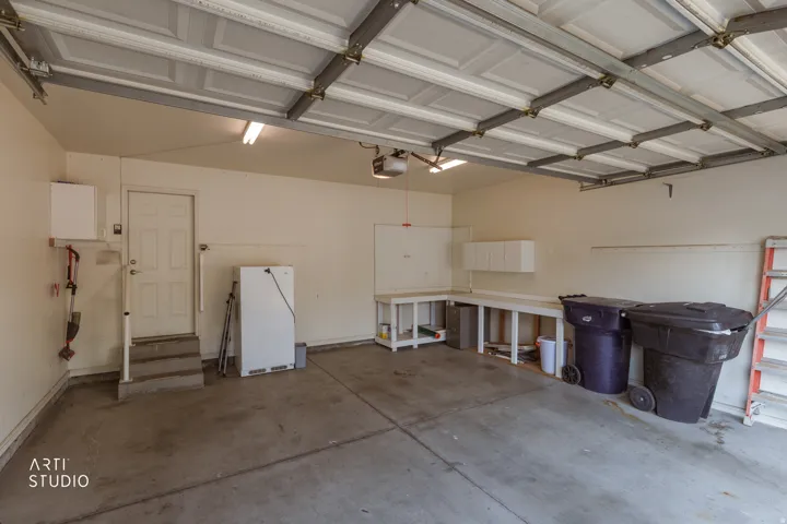 Spacious garage with polished concrete flooring, overhead LED lighting, and metal-framed ceiling structure