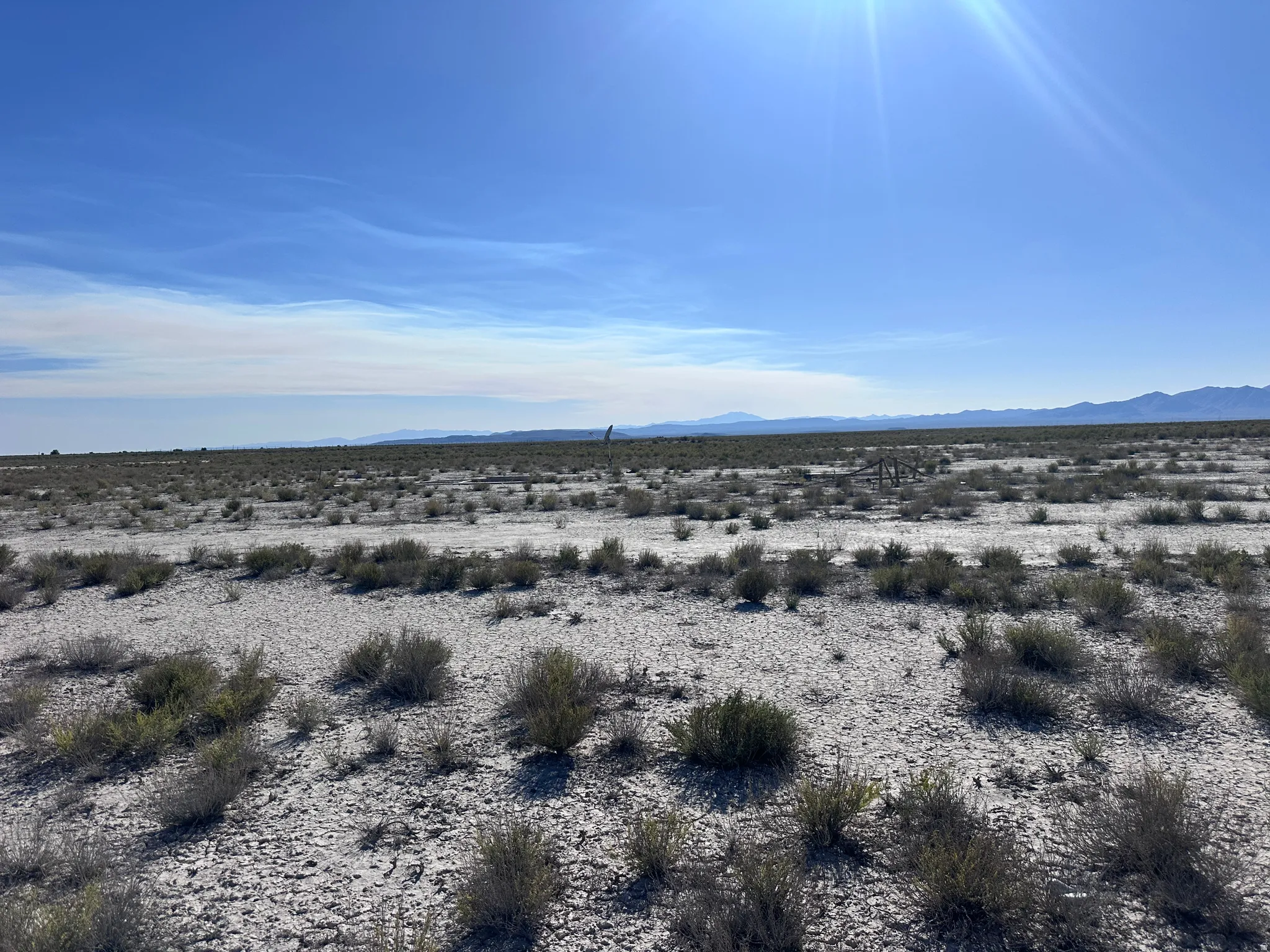 Expansive undeveloped land featuring natural desert vegetation, a clear blue sky, and distant mountain ranges