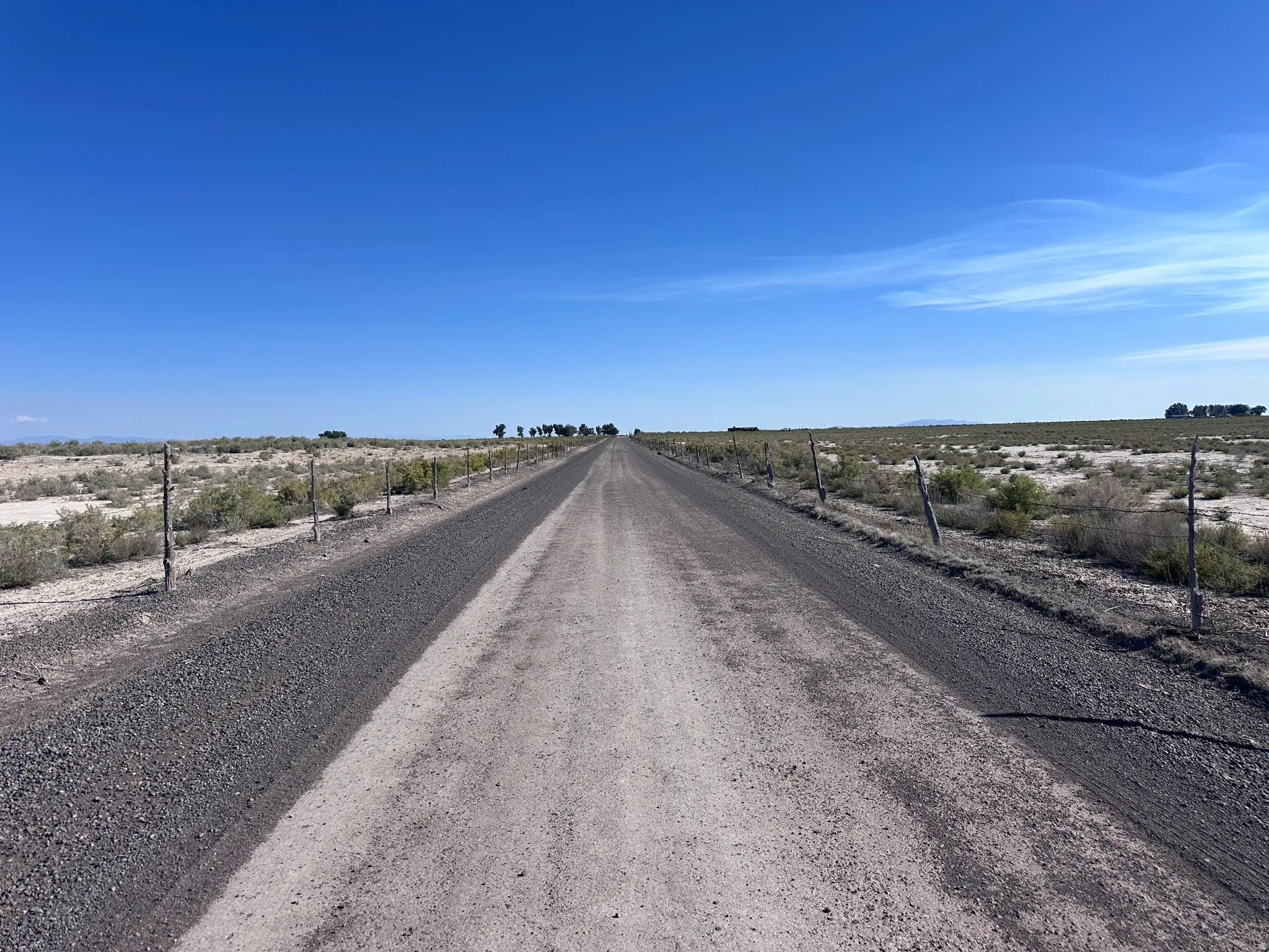 Expansive rural property featuring a well-graded gravel driveway extending across flat terrain with fencing lining both sides