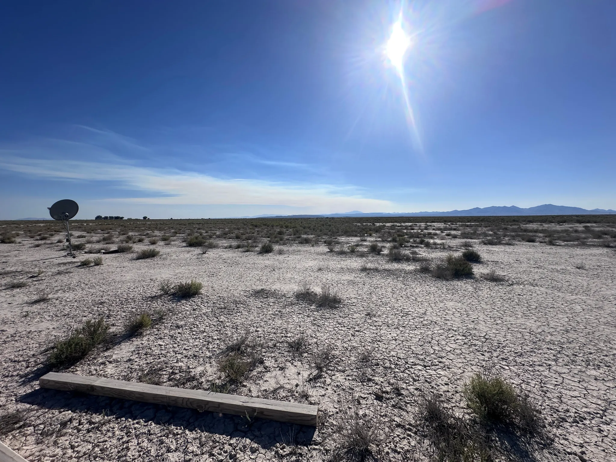 Expansive open land with a distinct cracked earth texture and scattered low-lying vegetation