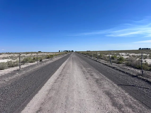 Expansive rural property featuring a well-graded gravel driveway extending across flat terrain with fencing lining both sides