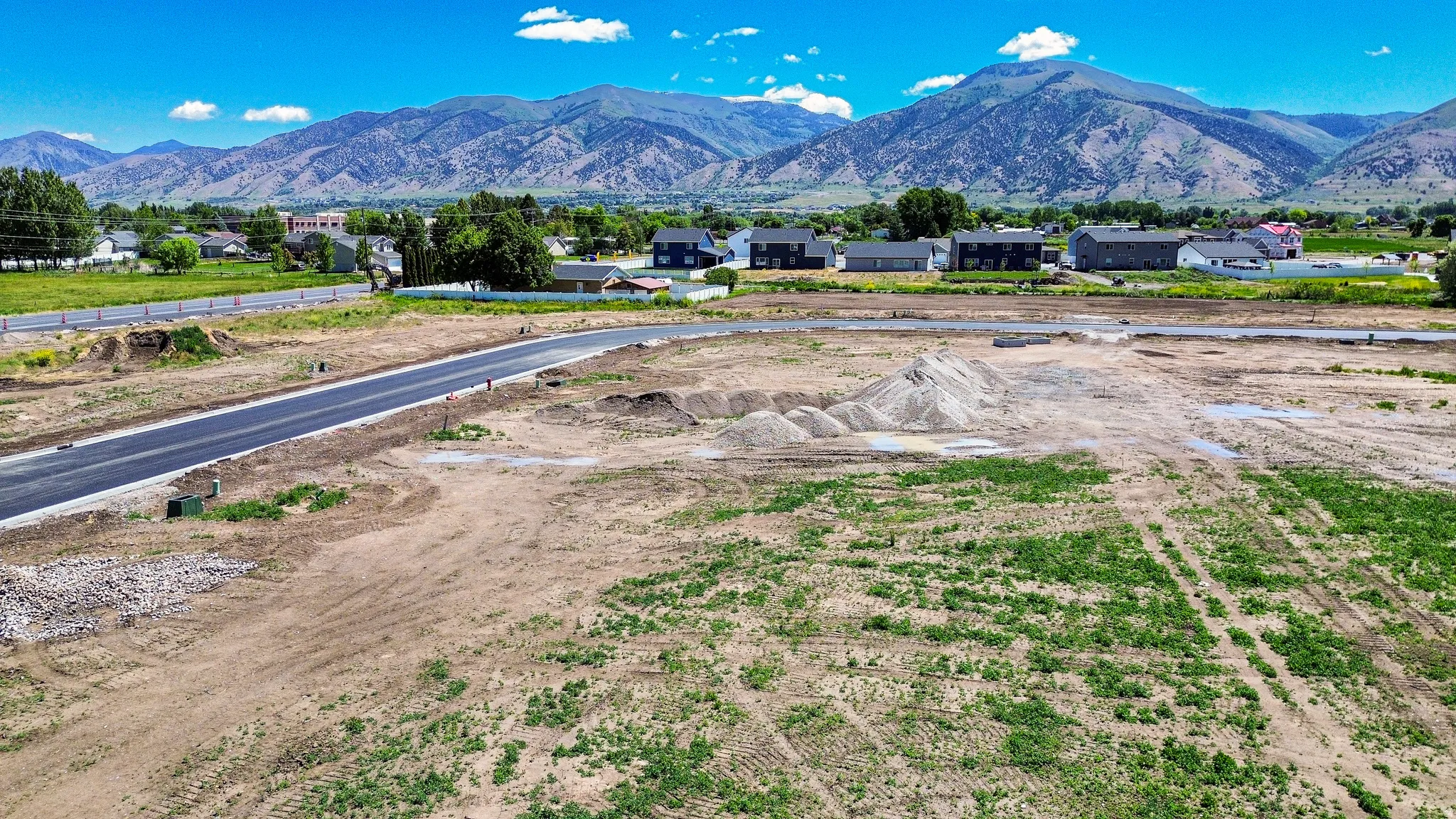 Developed land parcel featuring new asphalt paving, graded earth, and visible utility boxes