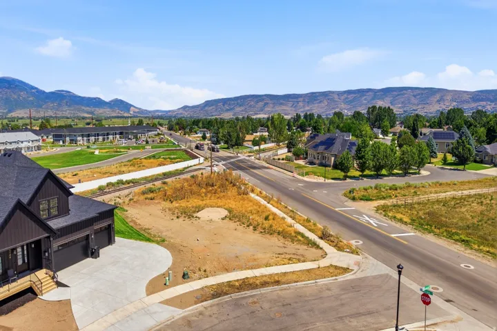 Aerial view of this new construction lot featuring finished concrete driveway, defined landscape borders with native plantings, and green roof visible on the adjacent home
