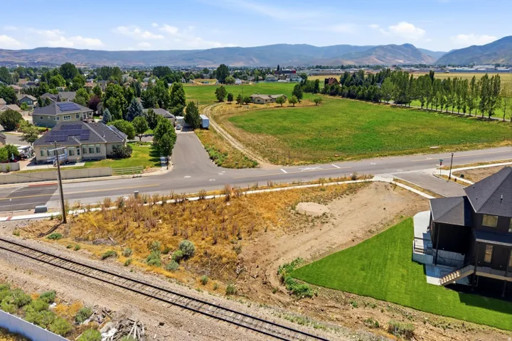 Expansive vacant lot with mature landscaping and newly established sod, situated along a paved road with railroad access