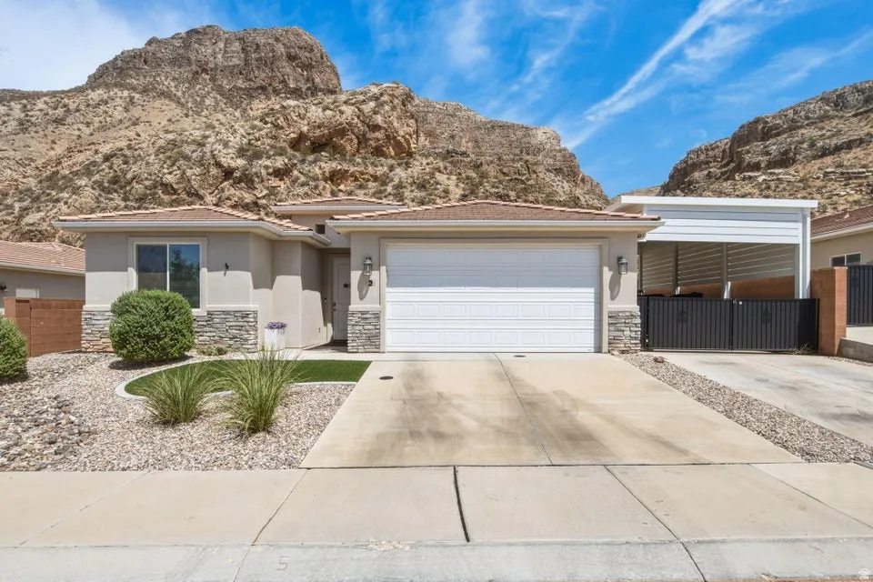 Stucco residence with a terracotta tile roof, integrated two-car garage, and a covered side carport