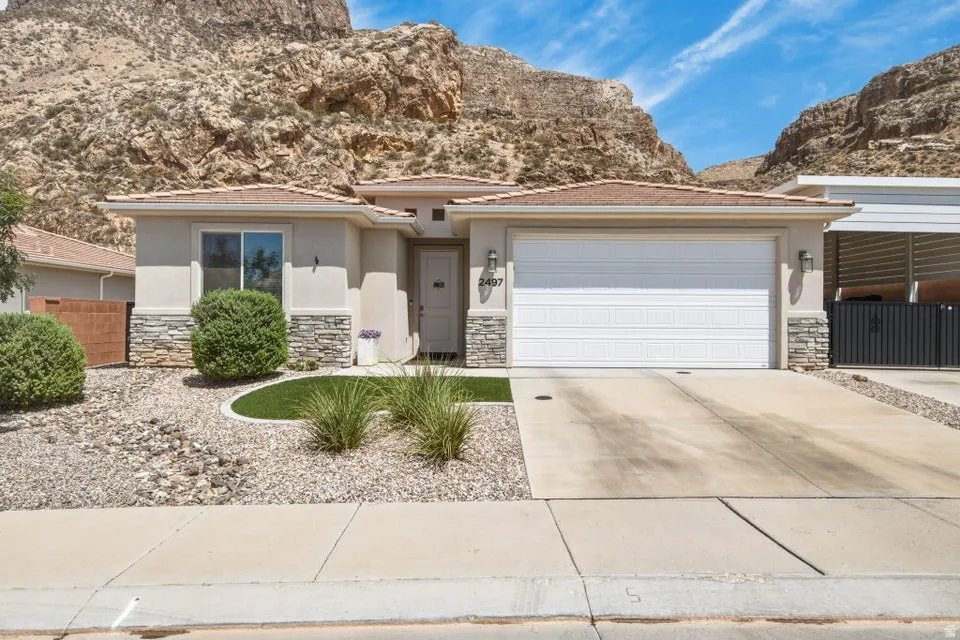 Stucco exterior featuring stone veneer accents and a two-car garage