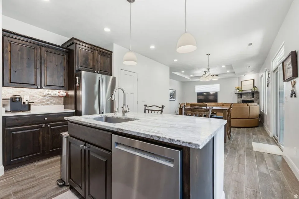 Kitchen featuring a large island with an undermount sink, stainless steel dishwasher, and light-toned countertop