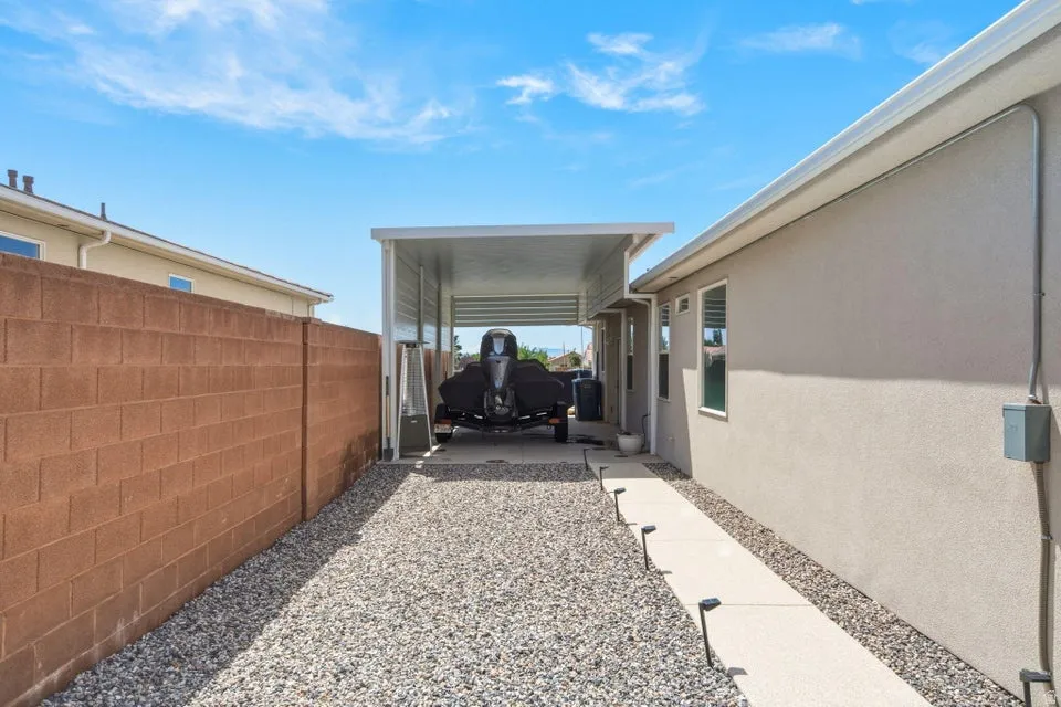 Side yard featuring a gravel driveway leading to a covered carport