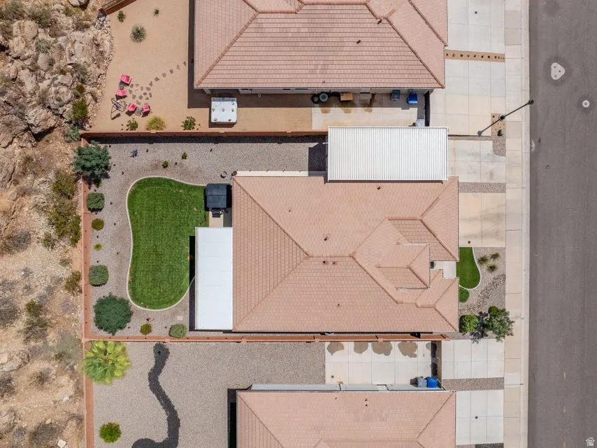 Aerial perspective showcasing a property with a tan tile roof, a manicured lawn area, and gravel landscaping