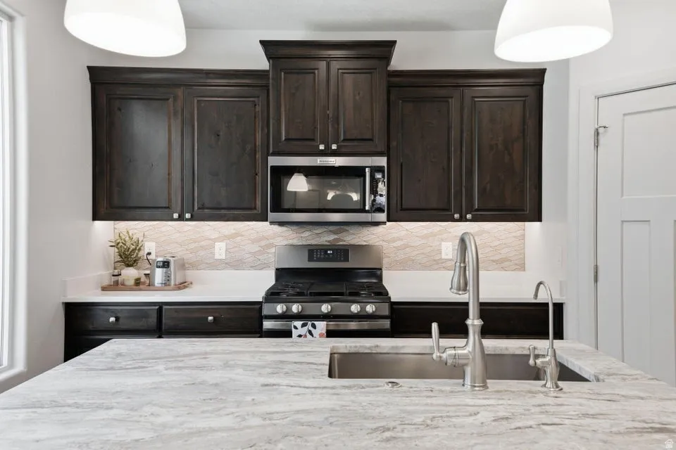 Gourmet kitchen featuring dark wood cabinetry with polished hardware, a black gas cooktop with stainless steel range hood, and a built-in microwave