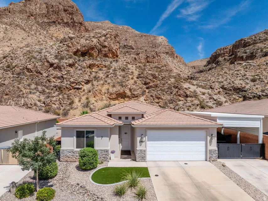 Modern single-story residence featuring a clean-lined stucco exterior with stone accents, positioned against dramatic natural terrain
