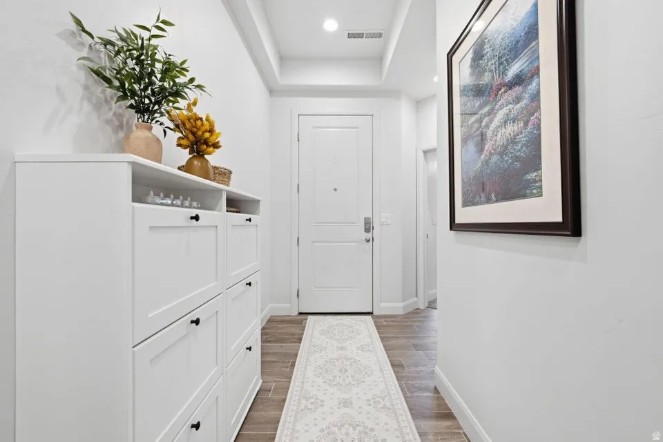 Entryway featuring wood-finish flooring, crisp white walls, and a recessed ceiling