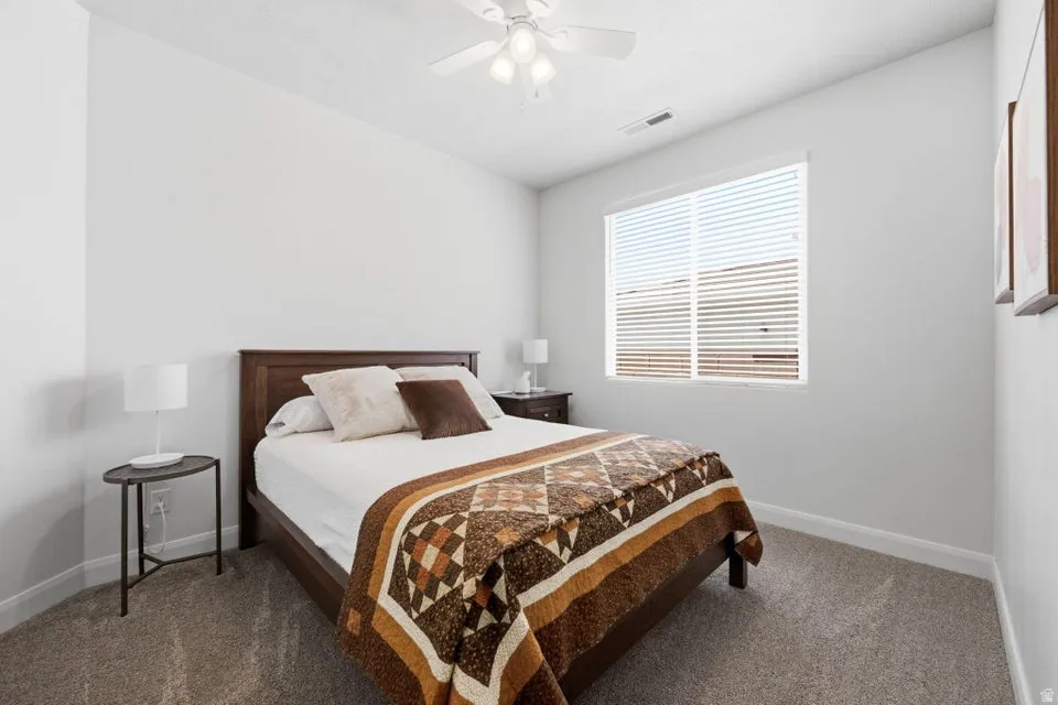 Spacious room featuring neutral paint, soft carpeting, a ceiling fan with integrated lighting, and a large window with horizontal blinds