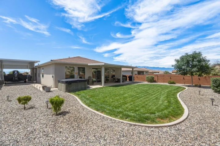 Expansive backyard featuring a manicured lawn area, gravel landscaping, and a covered patio