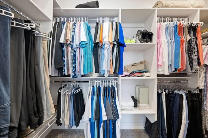 Custom closet system featuring white shelving and chrome hanging rods