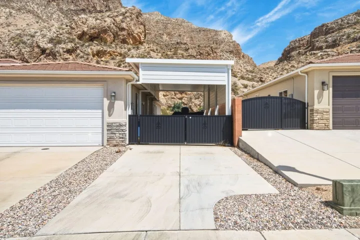 Exterior featuring a tan stucco finish, white garage door, stacked stone accents, and a brown tile roof