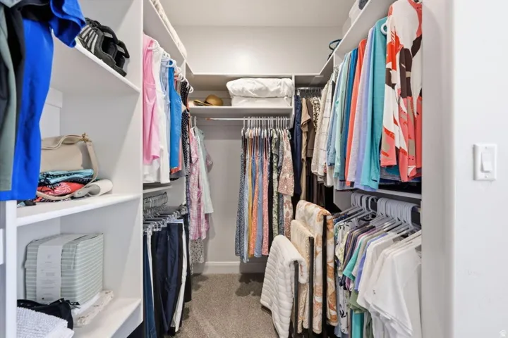 Walk-in closet featuring extensive built-in shelving and hanging rods, ample storage capacity, recessed lighting, and neutral finishes throughout