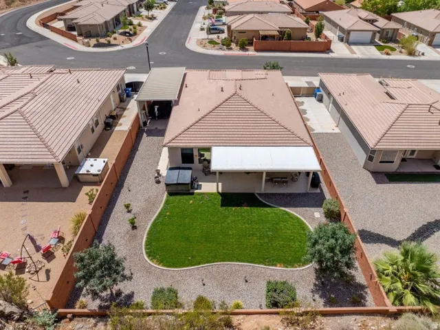 Aerial view showcasing a generously proportioned backyard featuring a lush, manicured lawn bordered by mature landscaping and established trees