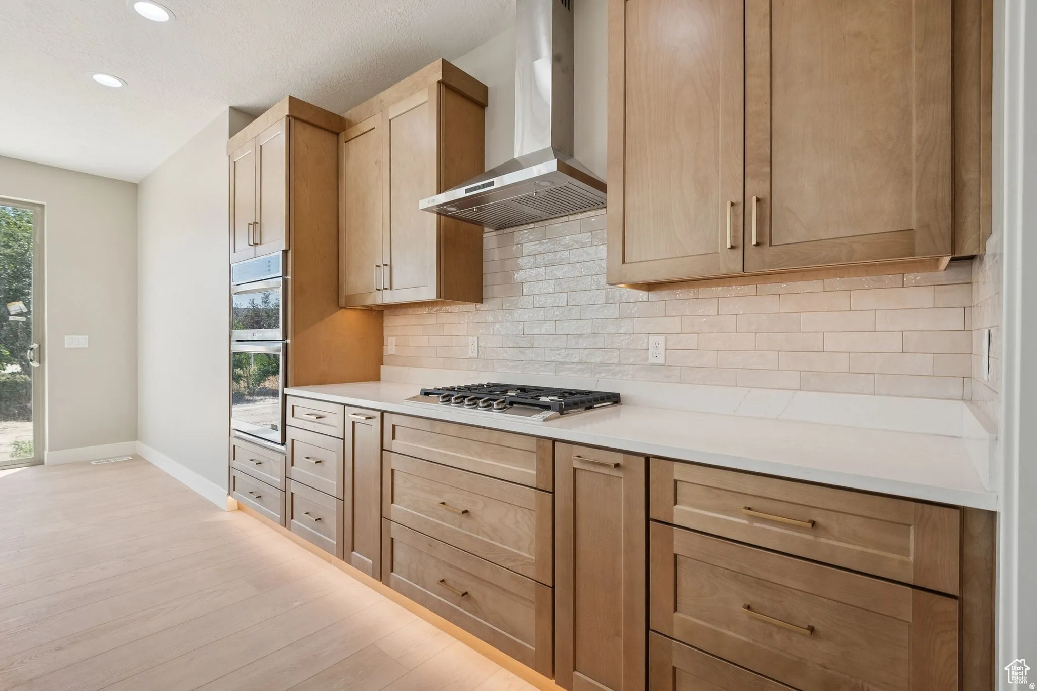 Chef's kitchen featuring custom wood cabinetry, stainless steel gas cooktop with professional-grade hood ventilation, and white subway tile backsplash
