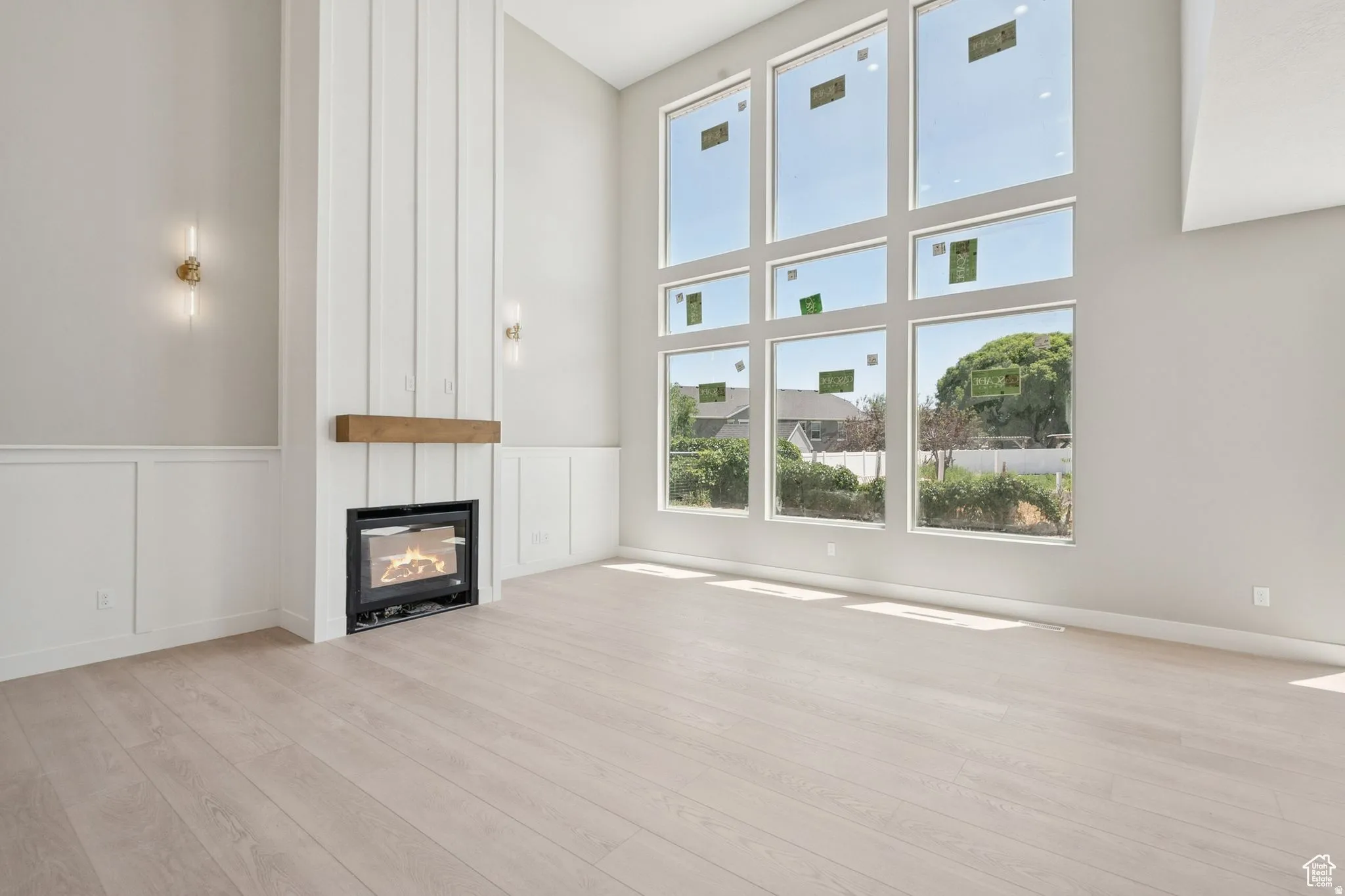 Bright, open living space showcasing soaring ceilings, expansive multi-pane windows flooding the room with natural light, and a wood-finish plank floor