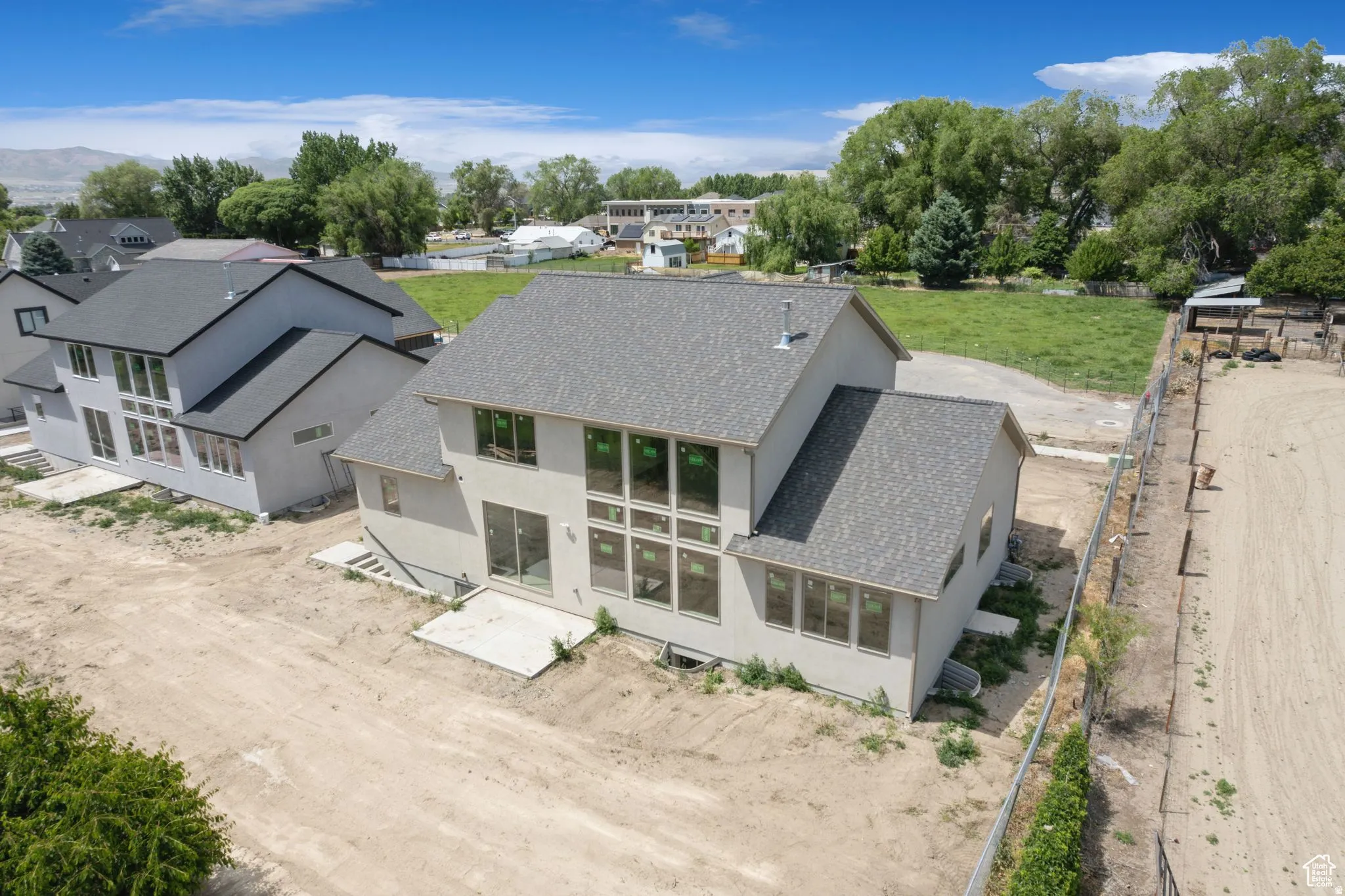 Contemporary stucco exterior featuring a multi-pane window configuration, durable asphalt shingle roofing, and a concrete patio
