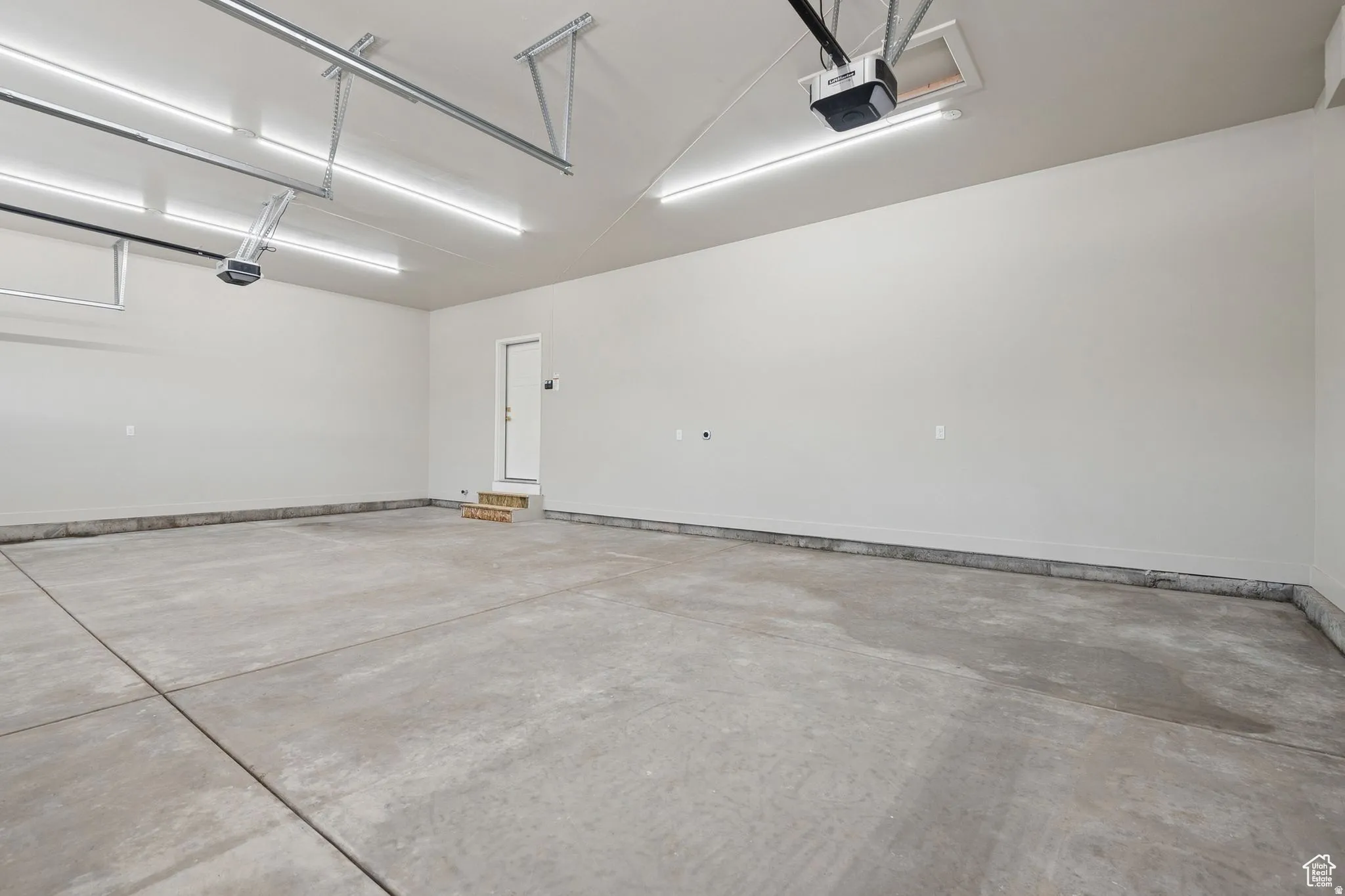 Spacious commercial or industrial space featuring polished concrete flooring, bright LED overhead lighting, and clean white walls with a protective base rail
