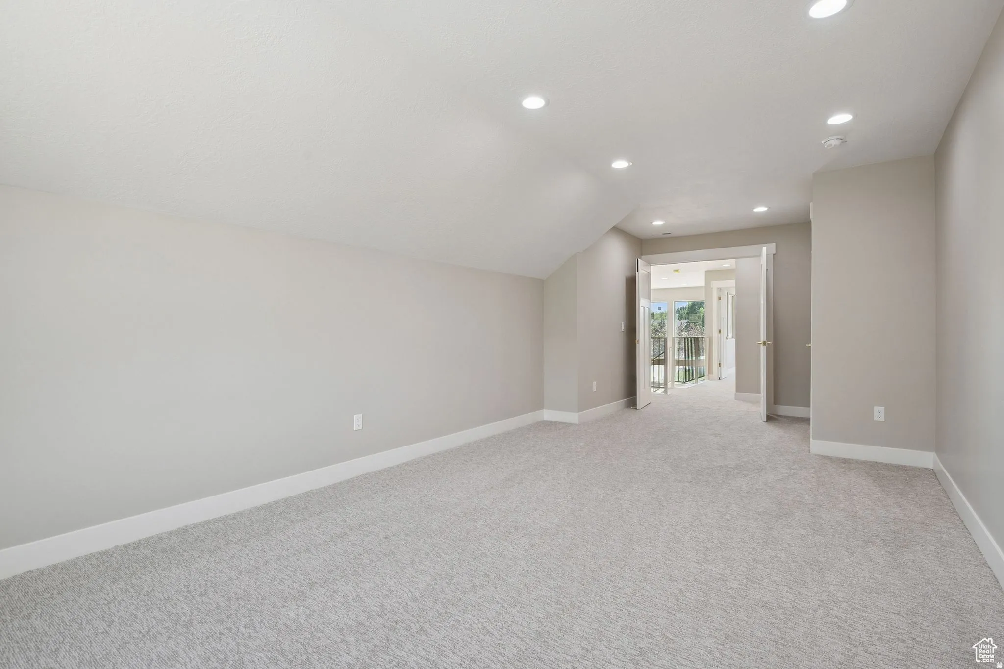 Spacious bonus room or secondary bedroom featuring recessed ceiling lighting, neutral carpet flooring, and abundant natural light from French doors
