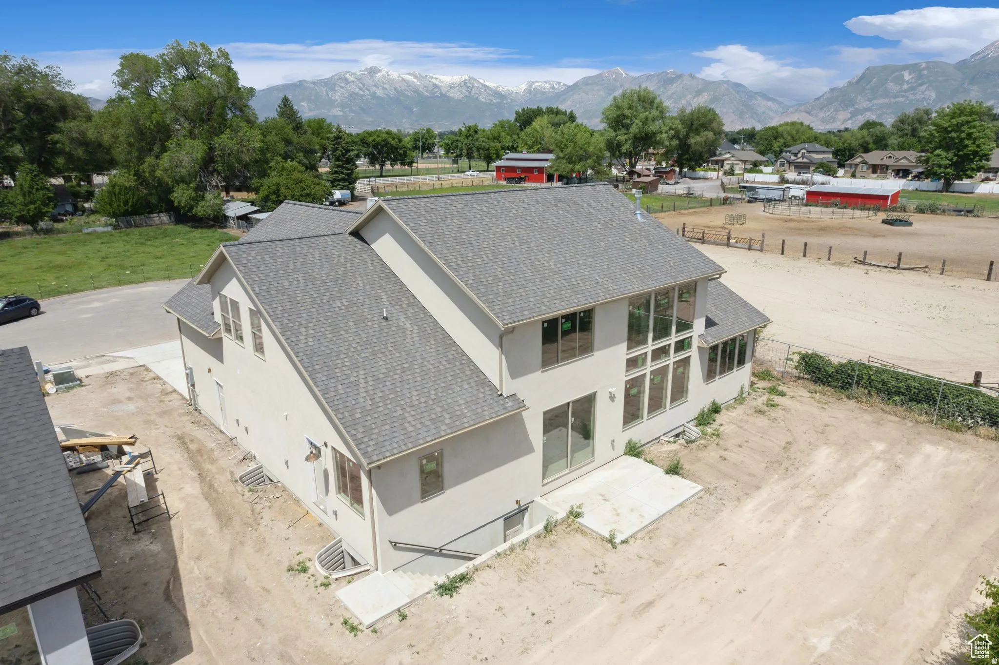 Modern two-story residence featuring a clean-lined architectural design with a steeply pitched asphalt shingle roof, light-colored exterior siding, and expansive multi-pane windows
