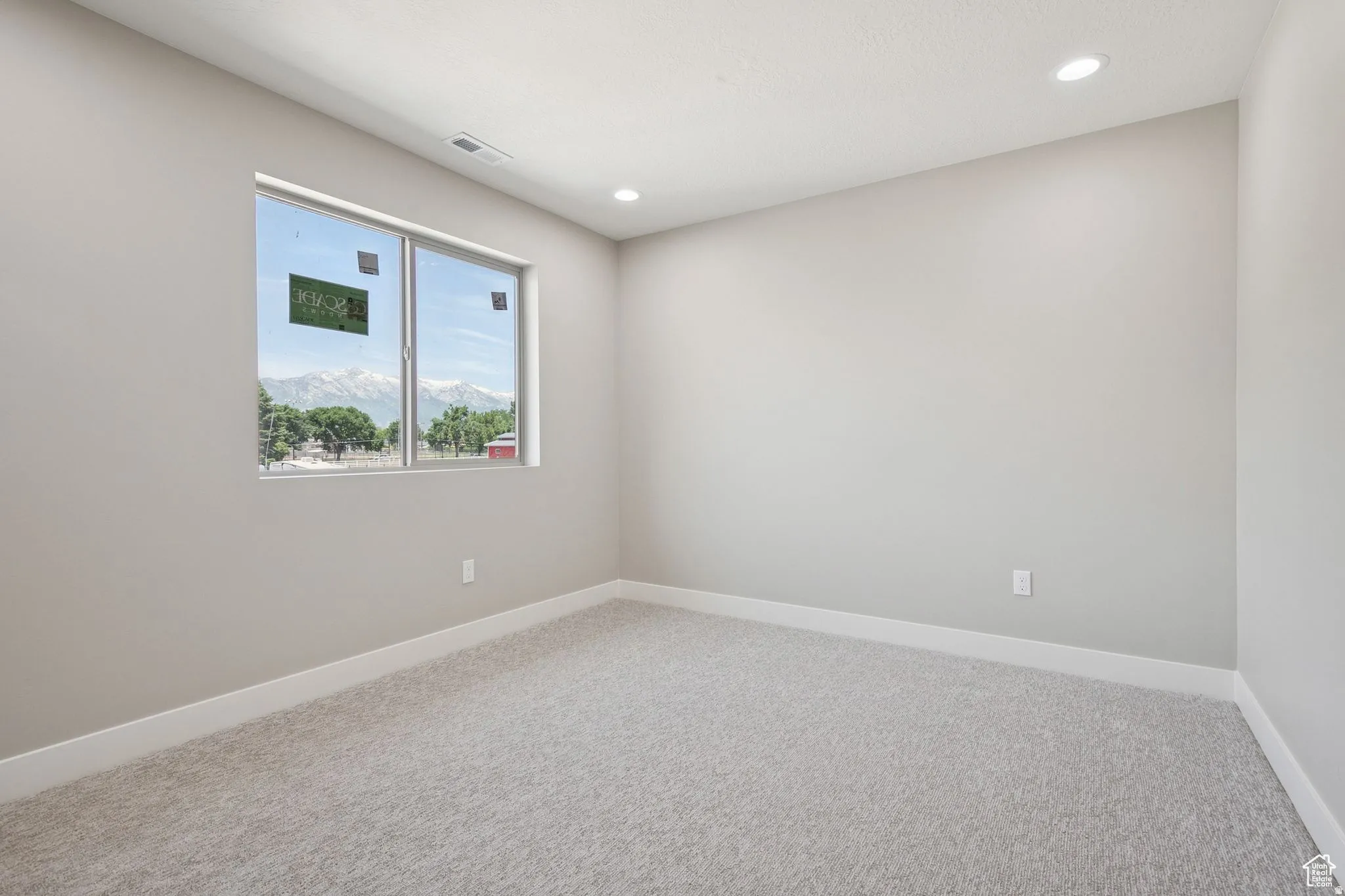 Bright secondary bedroom featuring neutral wall finishes, recessed ceiling lighting, and expansive carpet flooring