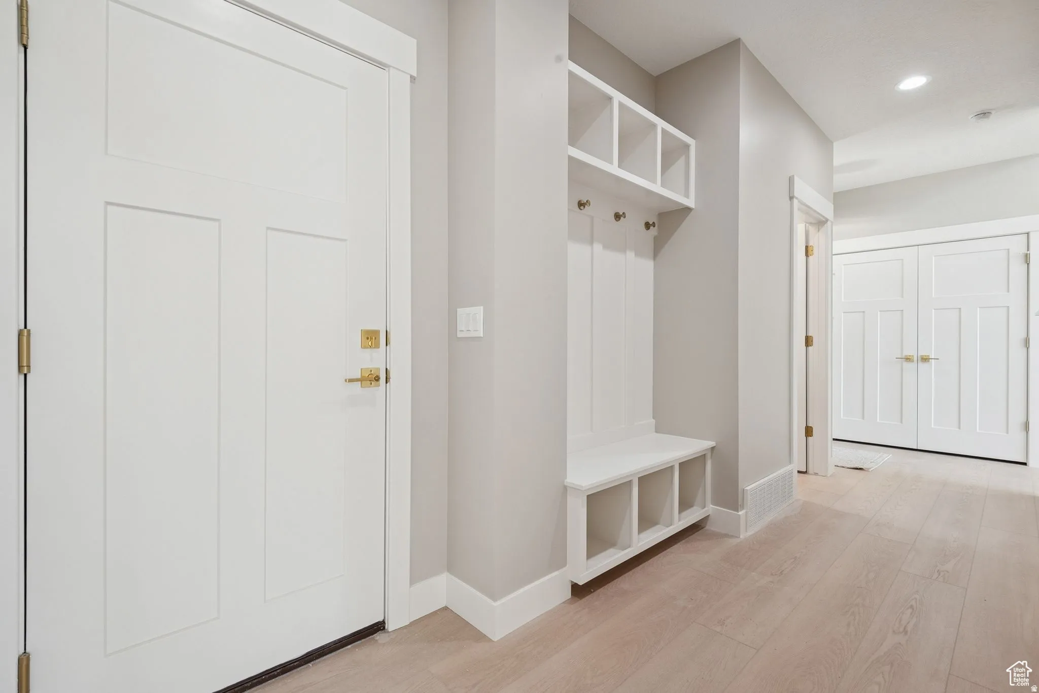 Entryway featuring built-in mudroom storage, light wood-finish flooring, and white trim