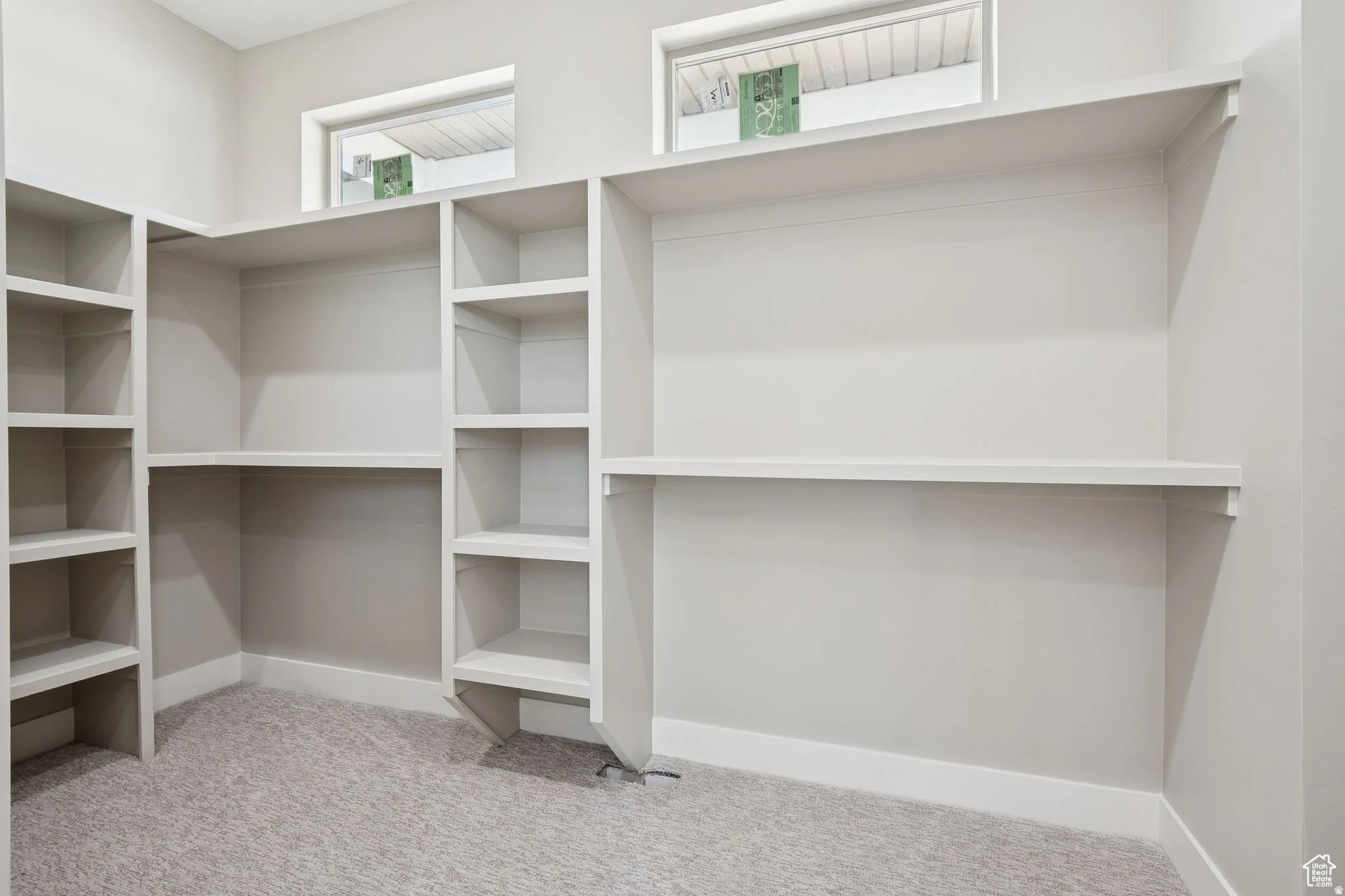Spacious walk-in closet featuring custom built-in shelving and cabinetry throughout, with multiple open shelves for organized storage and display