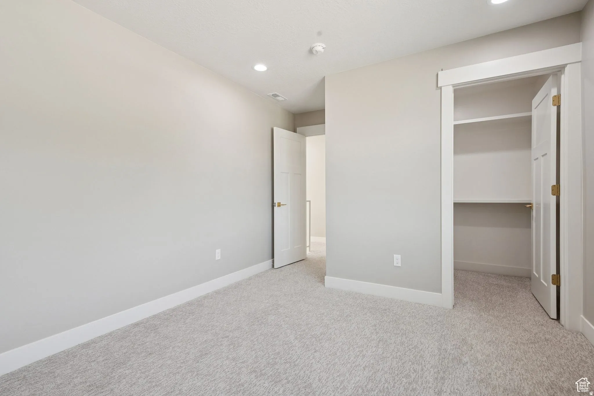 Spacious bedroom with neutral carpeting, recessed lighting, and dual reach-in closets with shelving