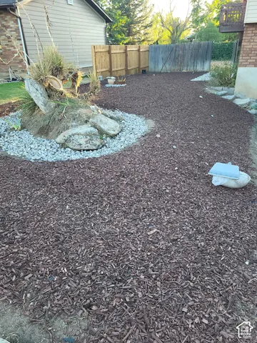 Wood chip ground cover, natural rock landscaping, and wood fence