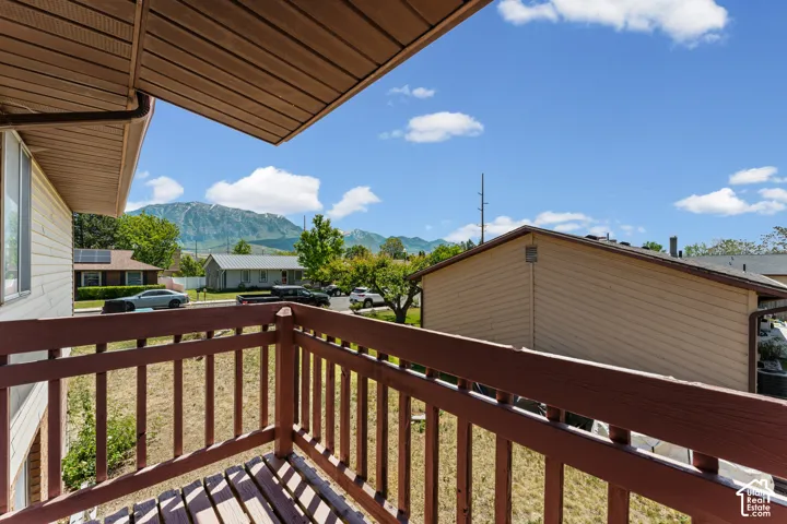 Outdoor balcony featuring wood-finish railing and decking, with an expansive mountain backdrop