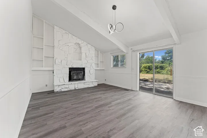 Bright and airy living space featuring gleaming wood-finish flooring, white shiplap accent wall with an integrated fireplace and built-in shelving, coffered ceiling detail, and sliding glass doors opening to outdoor space
