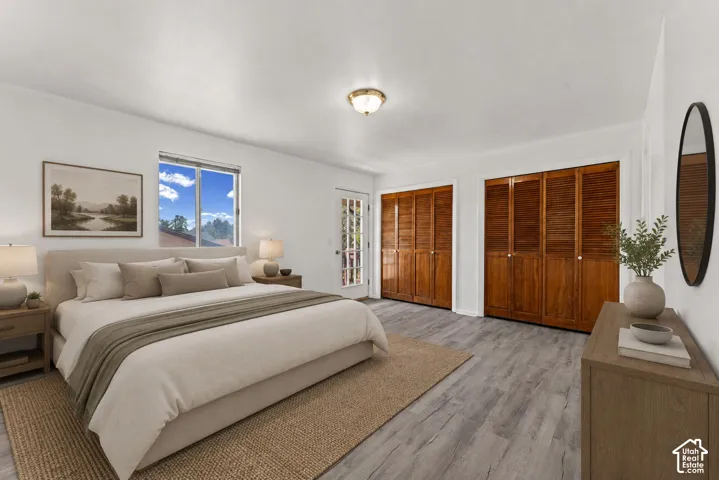 Spacious interior featuring two sets of wood-louvered bi-fold closet doors, a single glass-paneled door, and wood-finish flooring