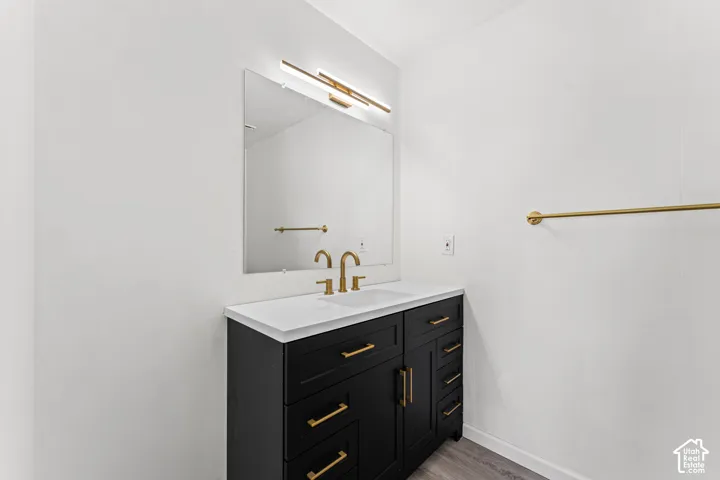 Bathroom vanity featuring a black cabinet, white countertop, gold-finish faucet, and coordinating gold-finish hardware