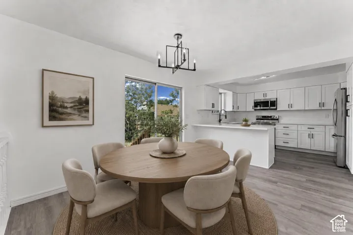 Open dining area featuring a round wood-finish pedestal table with seating for four, positioned to capture natural light from expansive glass doors and windows
