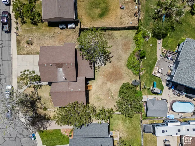 Detached home with brown shingle roofing, a concrete driveway, and mature trees