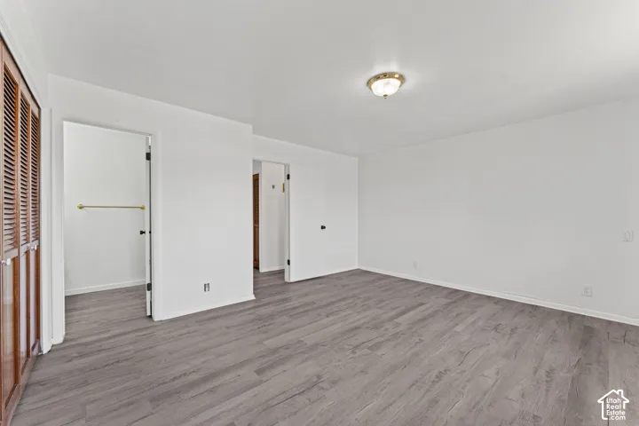 Primary Bedroom Suite featuring gleaming wood-finish flooring, an ensuite bathroom with frameless glass shower enclosure, dual entry doors, recessed ceiling lighting, and abundant natural light from multiple windows
