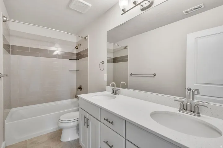 Spa-inspired dual-sink vanity featuring a white quartz countertop, soft-close cabinetry with chrome hardware, and polished chrome faucets