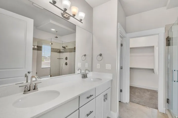 Dual vanity with white cabinetry and chrome hardware, featuring undermount sinks and a spacious quartz countertop
