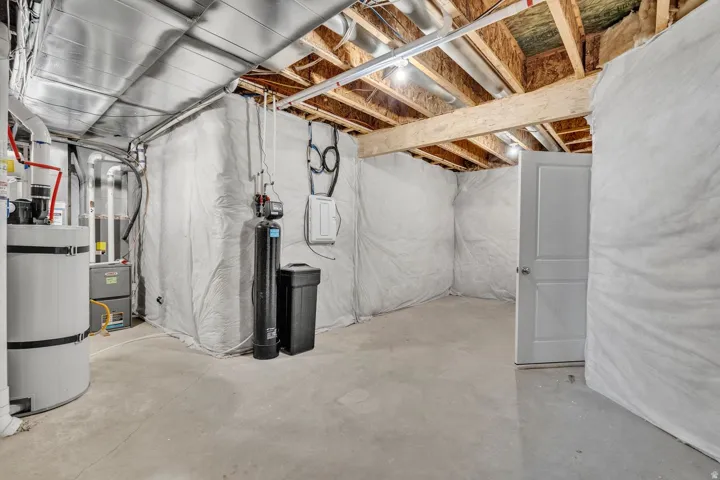 Unfinished basement featuring exposed wood joists, concrete flooring, and white interior doors