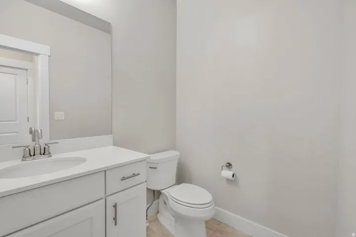 Bathroom vanity with a white countertop and integrated sink, brushed nickel faucet, and white cabinetry