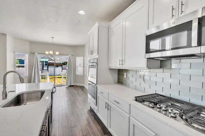 Modern kitchen featuring white shaker cabinetry, stainless steel appliances, a gas cooktop, and light quartz countertops
