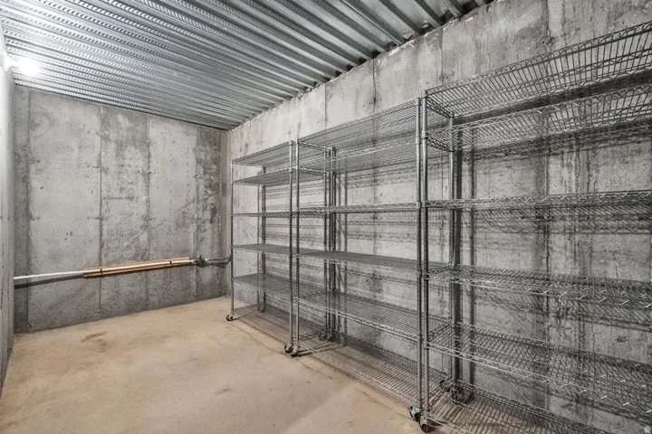 Versatile storage space featuring industrial-grade metal shelving units with wire mesh construction, concrete block walls, and polished concrete flooring