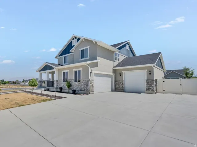 Modern two-story home featuring a clean-lined architectural design with stone and siding exterior, dual-bay garage with white overhead doors, and a generous concrete driveway