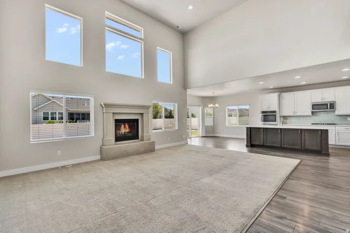 Open-concept great room featuring soaring ceilings with multiple skylights, a gas fireplace with built-in shelving, and seamless wood-finish flooring