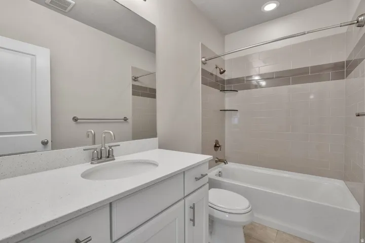 Spa-inspired secondary bathroom featuring a white vanity with dual-sink configuration, quartz countertop, and chrome faucetry
