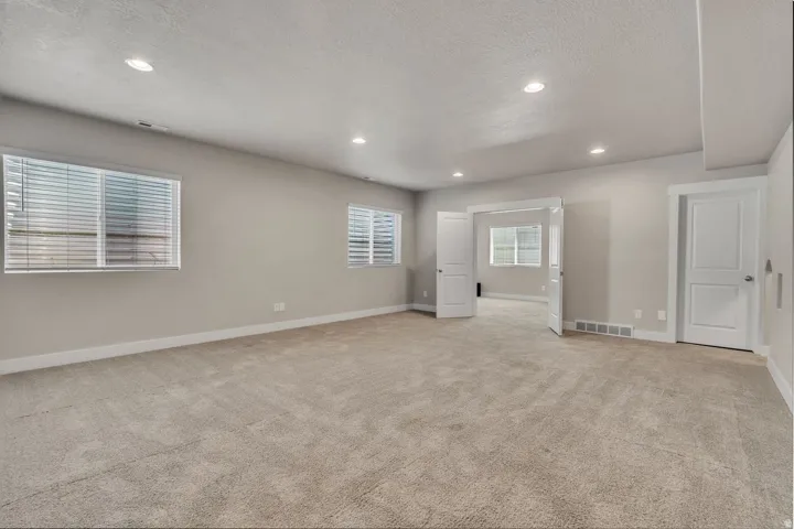Spacious primary living area featuring neutral wall finishes, recessed ceiling lighting, and plush carpet flooring throughout